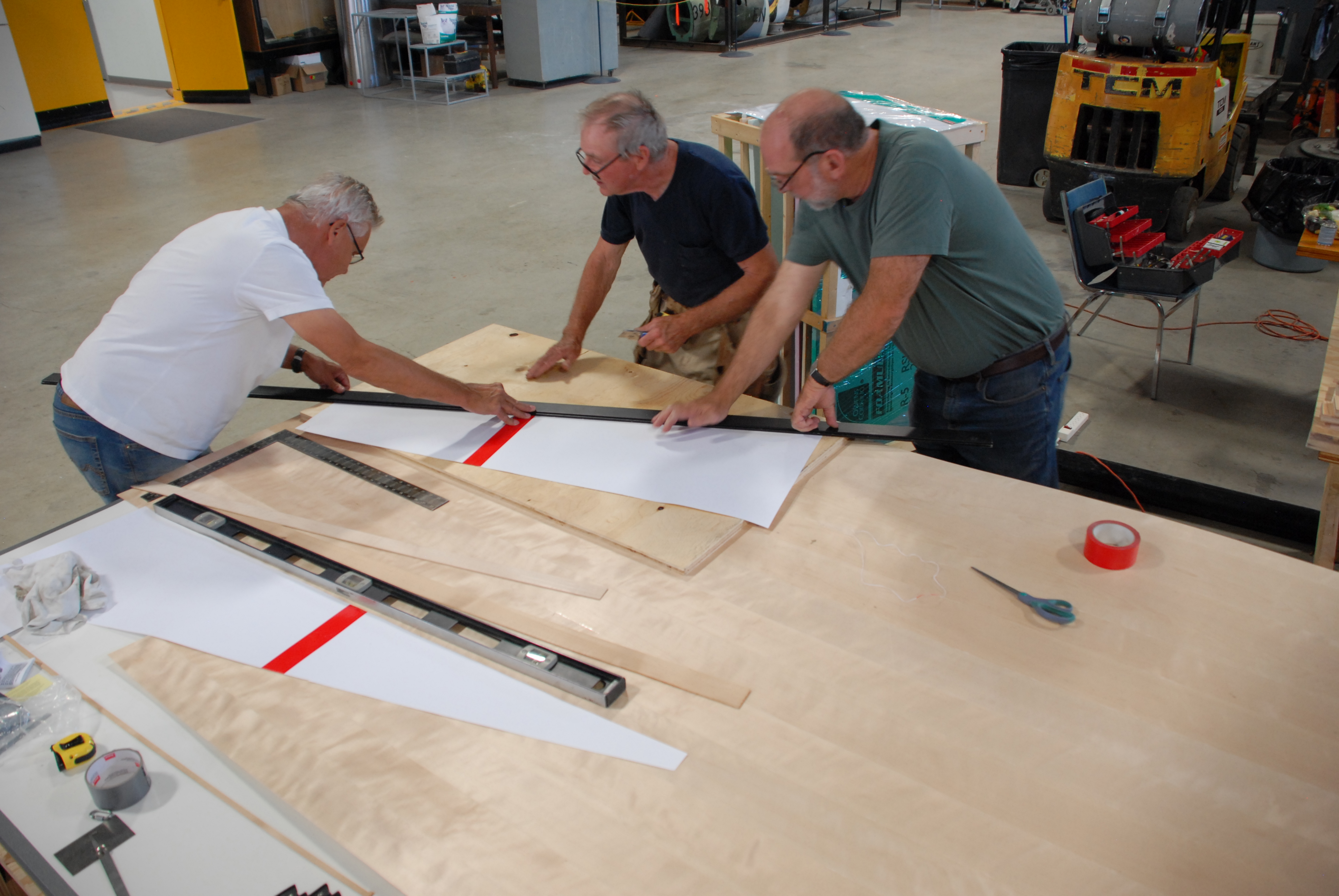 Dick, Roger and Jack cutting the first new skin for the Mosquito fuselage.