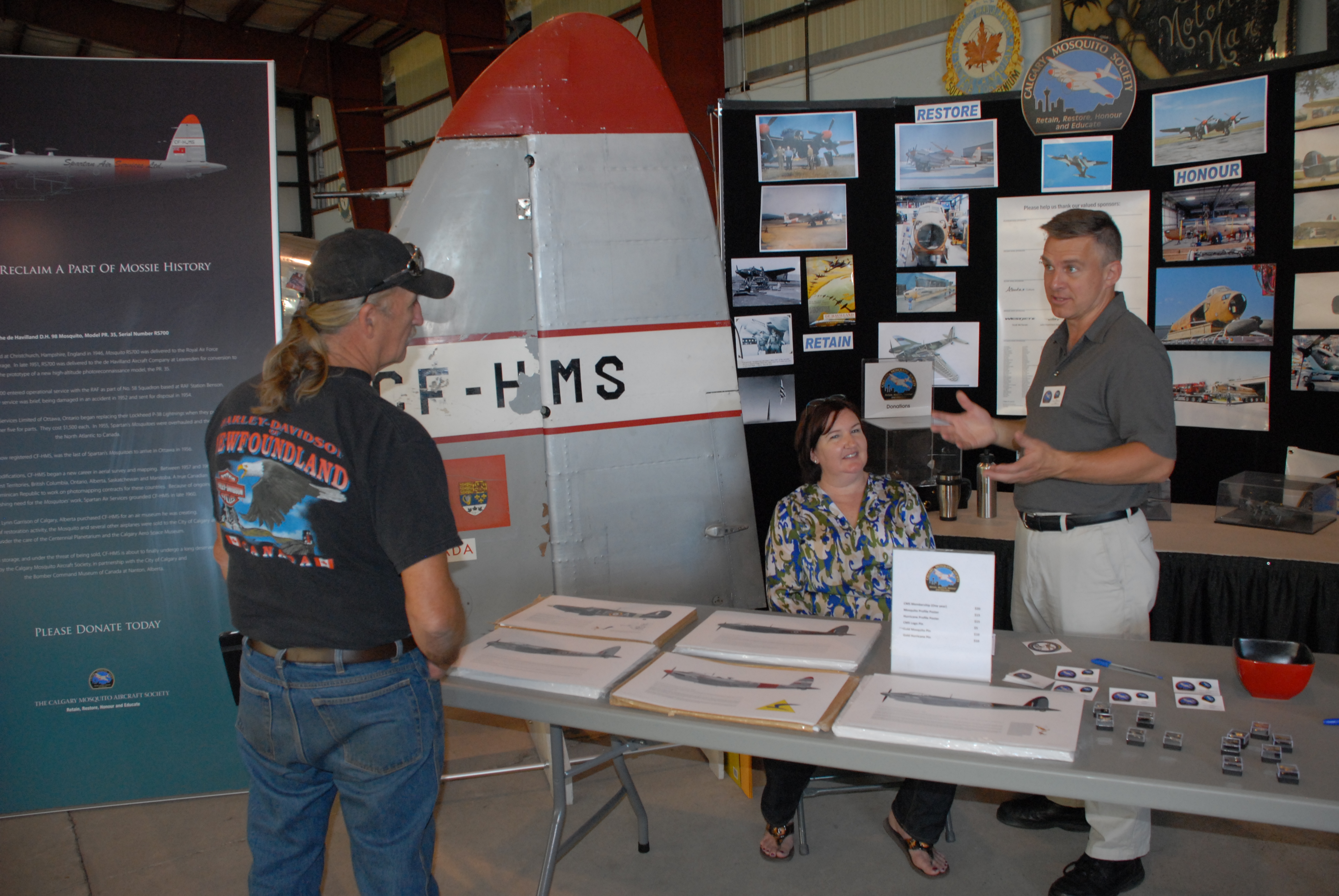 Board members Colette and Stéphane talk to a visitor during the July 4, Bikes and Bombers event at the Bomber Command Museum.